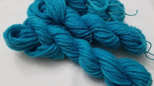 Three mini-skeins of wool yarn dyed blue.