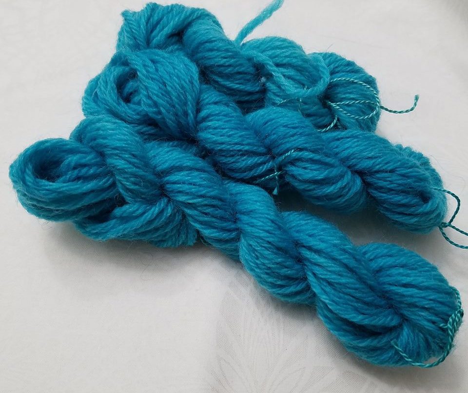 Three mini-skeins of wool yarn dyed blue.