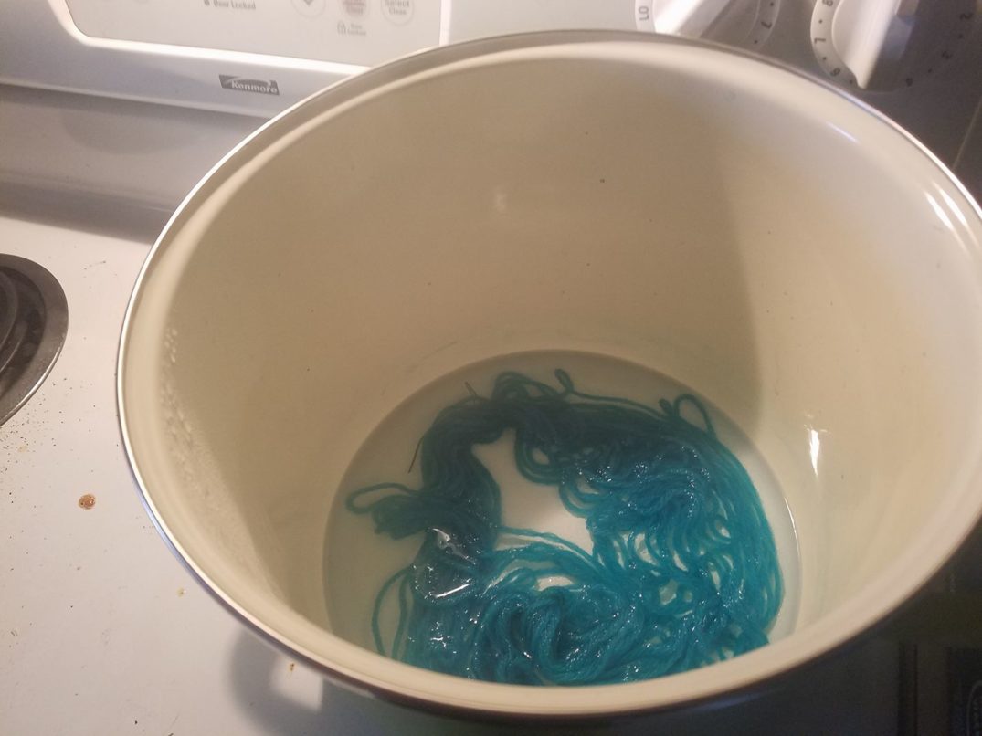Blue yarn in clear water in a dye pot.